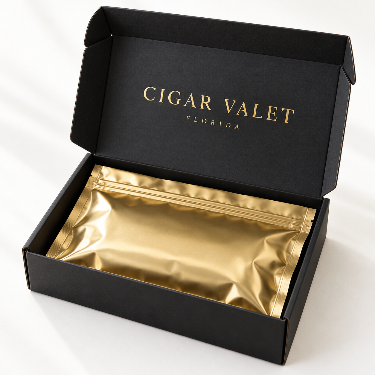 Gold protective bag inside an open black Cigar Valet Florida delivery box.